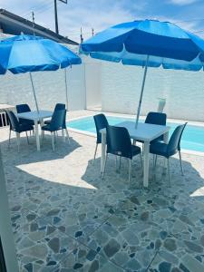 a group of tables and chairs with blue umbrellas at Atena Flats in Aracaju