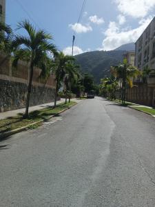 an empty street with palm trees and a mountain at Tu_refugio_playero in Caraballeda