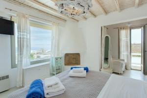 a white bedroom with a bed and a large window at Manolia Luxury Private house by Mykonian Kazarte in Kalo Livadi