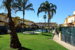 a park with palm trees and buildings and a fence at Preciosa casa cerca del mar in La Redondela