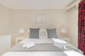 a white bedroom with a large bed with two pillows at Ocean Tides 35 in Bloubergstrand