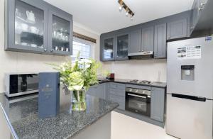 a kitchen with gray cabinets and a vase of flowers on a counter at Ocean Tides 35 in Bloubergstrand