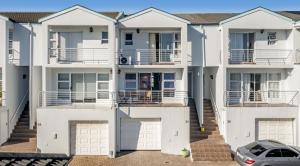 a row of white apartment buildings with a car parked in front at Ocean Tides 35 in Bloubergstrand