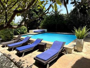 a group of lounge chairs next to a swimming pool at Villa Maua Exclusive in Matemwe