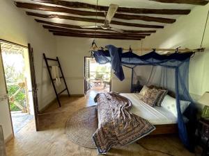 a bedroom with a bed with a blue canopy at Villa Maua Exclusive in Matemwe