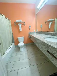 a bathroom with a toilet and a sink and a mirror at Pecan Valley Inn & Suites in San Antonio