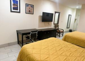 a bedroom with two beds and a desk and a television at Pecan Valley Inn & Suites in San Antonio