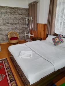 1 dormitorio con 1 cama blanca grande y escalera en Yalung Homestay, en Darjeeling