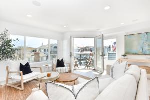 Una sala de estar con muebles blancos y grandes ventanales. en Luxury 3 Bedroom walk to Beach & Pier, en Newport Beach