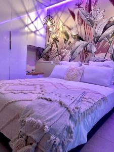a large white bed in a room with plants on the wall at Diadora au magnifique panorama - Studio neuf de prestige vue mer in Le Diamant