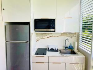 a small kitchen with a refrigerator and a sink at Diadora au magnifique panorama - Studio neuf de prestige vue mer in Le Diamant