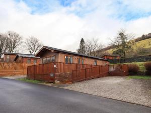 a wooden house with a fence and a driveway at Lakeland View Lodge in Windermere