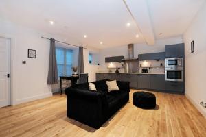 un salon avec un canapé noir et une cuisine dans l'établissement One of a kind Historic 3 bedroom apartment, à Aberdeen