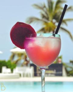 a drink in a martini glass next to a pool at Diadora au magnifique panorama - Studio neuf de prestige vue mer in Le Diamant