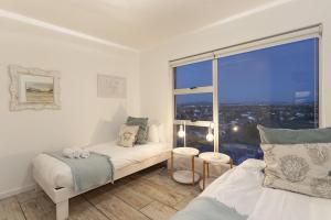 a bedroom with two beds and a large window at Ocean View B901 in Bloubergstrand