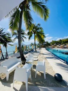 een resort met witte stoelen en een zwembad bij Diadora au magnifique panorama - Studio neuf de prestige vue mer in Le Diamant