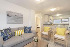 a living room with a couch and chairs and a kitchen at Ocean View B901 in Bloubergstrand