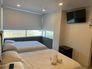 a bedroom with two beds and a flat screen tv at Borabora hotel in San Andrés