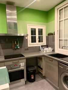 uma cozinha com paredes verdes e utensílios de aço inoxidável em Chambre charmante entre Paris et Disney em Noisy-le-Grand