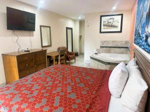 a bedroom with a bed and a bathroom with a tub at Pecan Valley Inn & Suites in San Antonio