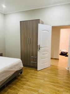 Schlafzimmer mit einem Bett und einem Holzschrank in der Unterkunft Short And Long Stay Six Bedroom Apartment in Tema
