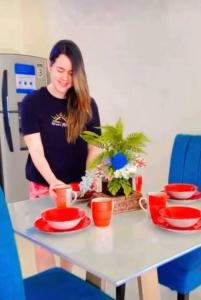 a woman standing in front of a table with red plates at Departamento Mar de Cristal in Santa Elena