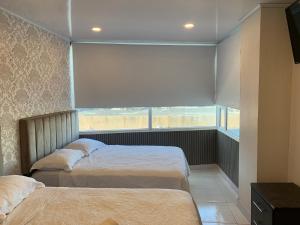 2 camas en un dormitorio con ventana grande en Borabora hotel, en San Andrés
