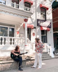 two people playing guitar and a man playing a guitar at Auberge Saintlo Montréal Hostel in Montreal