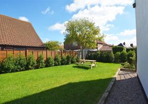 a backyard with a picnic table in the grass at BackToFront Cottage in Briston