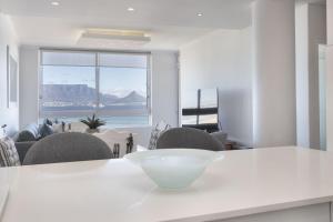 a white kitchen with a table with a bowl on it at Portico 704 in Bloubergstrand
