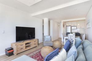 a living room with a blue couch and a tv at Portico 704 in Bloubergstrand