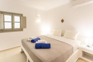 a white bedroom with a bed with blue towels on it at Villa Anemoni by Mykonian Kazarte in Kalafatis
