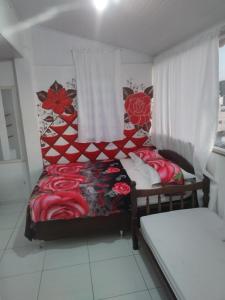 a bedroom with a bed with red flowers on it at Suítes da Erô in Arraial do Cabo