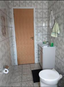 a bathroom with a toilet and a sink and a door at POUSADA MALU in Bragança Paulista