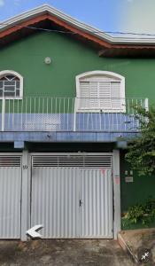 ein grünes Haus mit zwei Garagentüren und einem Balkon in der Unterkunft POUSADA MALU in Bragança Paulista