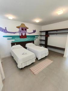 Cette chambre comprend deux lits et un tableau mural. dans l'établissement Villa dos Graffitis Pousada, à Morro de São Paulo