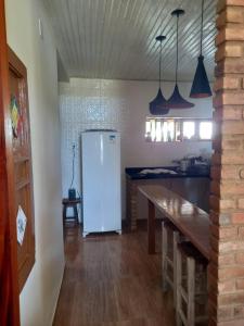 eine Küche mit einem weißen Kühlschrank und einem Tisch in der Unterkunft Chacara Delfino in Indiaroba