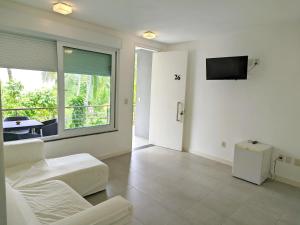 a white room with a bed and a tv at Villa dos Graffitis Pousada in Morro de São Paulo