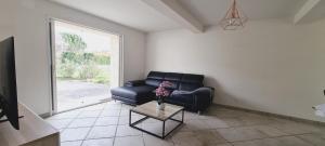 uma sala de estar com um sofá preto e uma mesa em Le Rouge Gorge à 12 minutes d'Eurexpo em Genas