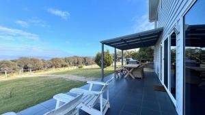 a porch with chairs and a picnic table on a house at Manfield Seaside Bruny Island in Alonnah