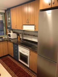 uma cozinha com utensílios de aço inoxidável e armários de madeira em Ponteareas Precioso apartamento . VUT-PO-011959 em Ponteareas
