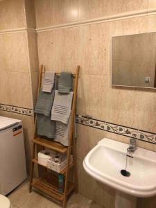 a bathroom with a sink and a shelf with towels at Ponteareas Precioso apartamento . VUT-PO-011959 in Ponteareas