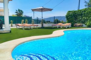 una piscina con sillas y sombrilla en Villa Anturium by Villa Plus, en Beniarbeig