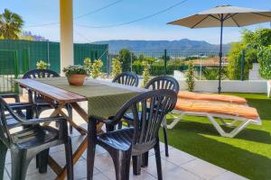 uma mesa com cadeiras e um guarda-sol num pátio em Villa Anturium by Villa Plus em Beniarbeig