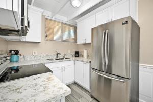una cocina con nevera de acero inoxidable y armarios blancos en 2 Bedroom Upstairs Apt 1 block from the beach! en Newport Beach