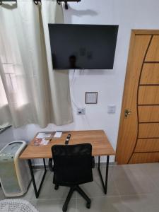 a wooden table with a chair and a television on a wall at Studio fantástico in São Paulo