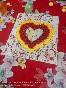 a heart shaped cake on a table with flowers at JA INT in Dhaka