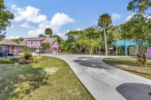 una entrada con una casa rosa y árboles en 2 BR Jensen Beach Tropical Resort, en Fort Pierce