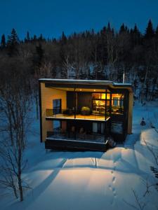 uma casa moderna na neve à noite em Le Zéphyr - Domaine Maelstrom em Lac-Beauport