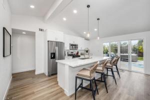 a kitchen with white walls and a large island with bar chairs at Spacious Home with 7 Beds minutes from Mission Bay in San Diego